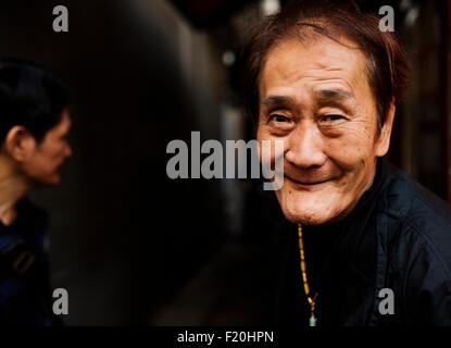 Portrait of senior man wearing necklace smiling at camera Banque D'Images