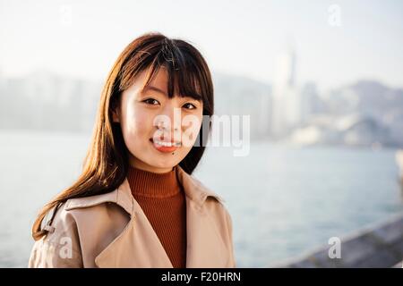 Portrait de jeune femme avec de longs cheveux en face de l'eau à la caméra à smiling Banque D'Images