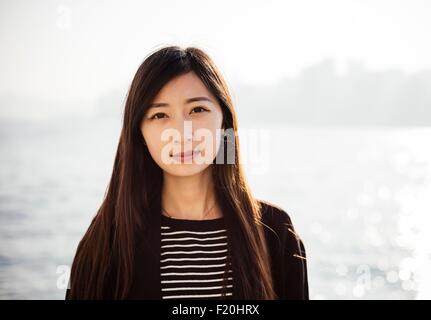 Portrait de jeune femme avec de longs cheveux de brunette wearing haut rayé looking at camera Banque D'Images