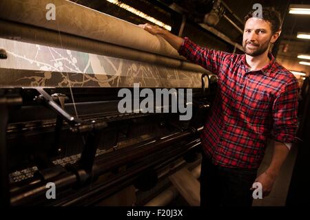 Portrait of male weaver à côté de vieille machine à tisser dans l'usine de textile Banque D'Images