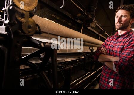 Portrait de jeune homme weaver et vieille machine à tisser dans l'usine de textile Banque D'Images