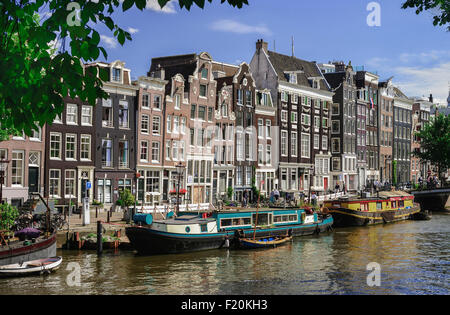 Pays-bas, Noord Holland, Amsterdam, le long du canal typique de Herengracht scène de maisons hautes et péniches par le sideawalk. Banque D'Images