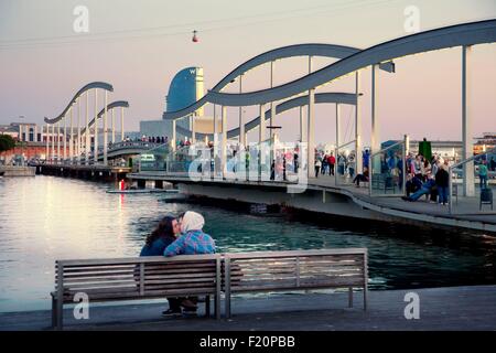 Espagne, Catalogne, Barcelone, le Vieux Port, Vieux Port, Port Vell, Rambla de Mar pont, un couple s'embrasser sur un banc et l'hôtel W en arrière-plan Banque D'Images