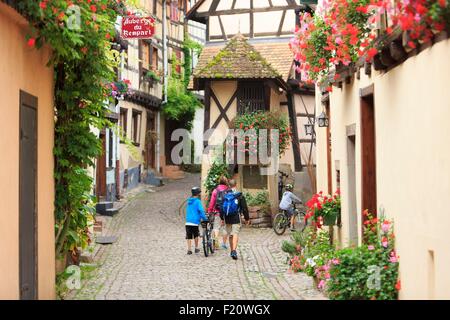 France, Alsace, Route des Vins d'Alsace, Eguisheim étiqueté Les Plus Beaux Villages de France (les plus beaux villages de France), les cyclistes et l'architecture de la rue des Remparts (rue des Remparts) Banque D'Images