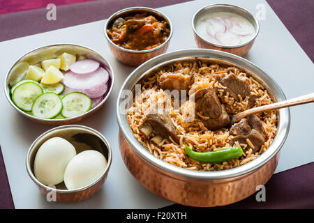 Vue rapprochée de la partie supérieure de délicieux biryani de mouton (agneau) servi dans des ustensiles en cuivre authentique avec des côtés. Banque D'Images