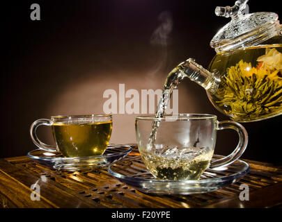 Photo horizontale, de la théière en verre tasse thé vert en débit sur fond brun, cérémonie du thé Banque D'Images