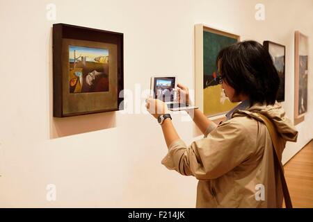 United States, New York, Manhattan, Musée d'Art Moderne (MOMA), Femme photographier une peinture de Salvador Dali, la persistance de la mémoire Banque D'Images