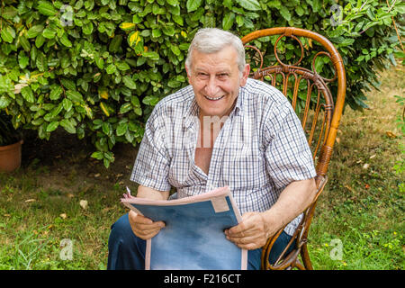 Retraite paisible, vieil homme lit le journal dans le jardin Banque D'Images