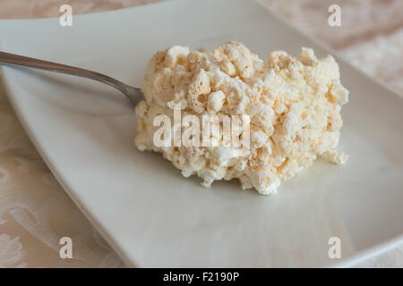 La meringue italienne tranche de gâteau à la crème et des écrous sur la plaque blanche. Banque D'Images