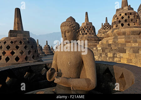 L'Indonésie, de Java, Borobudur, Bouddha assis sur le niveau supérieur allumé au début de la matinée, soleil chaud, entouré de stupas Banque D'Images