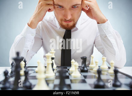 Pensive businessman leaning over échiquier Banque D'Images