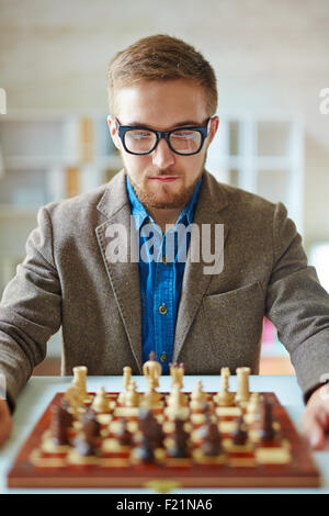 Serious businessman looking at chess on chessboard Banque D'Images