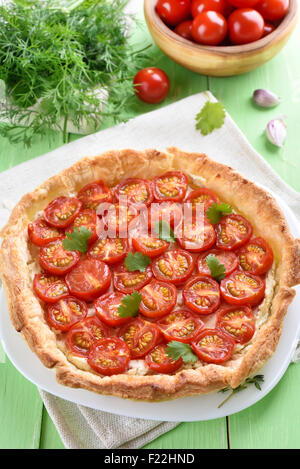 Tarte aux tomates et fromage et sur plaque blanche sur table en bois vert Banque D'Images