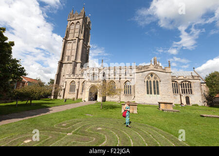 Une femme marche autour du labyrinthe Tercentennial en face de l'église de St Jean le Baptiste, la ville de Glastonbury, Somerset UK Banque D'Images