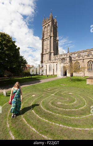 Une femme marche autour du labyrinthe Tercentennial en face de l'église de St Jean le Baptiste, la ville de Glastonbury, Somerset UK Banque D'Images