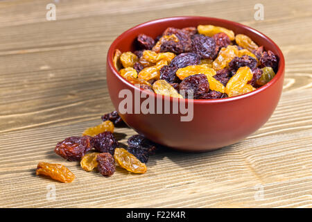 Raisins secs dans brown dich sur table en bois Banque D'Images