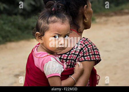 Candid portrait of a cute baby népalais à cheval sur le dos de sa grand-mère Banque D'Images