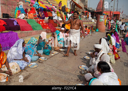 Un Pandit (prêtre et saint homme qui accomplit des cérémonies) mène des puja (prière) avec les pèlerins sur les ghats de Varanasi Banque D'Images