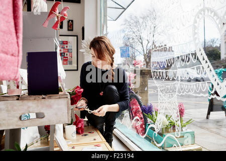 Une femme mature dans une boutique de cadeaux par la fenêtre, tenant une petite étoile. Banque D'Images