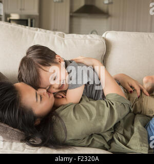 Une femme allongée sur un canapé, souriant, de câliner son jeune fils. Banque D'Images