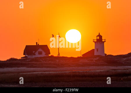 Un phare sur la plage, un moulin à turbine et d'un coucher du soleil. Banque D'Images