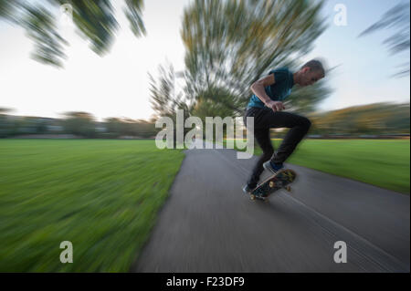Un adolescent skateboards dans un parc de Londres au coucher du soleil Banque D'Images