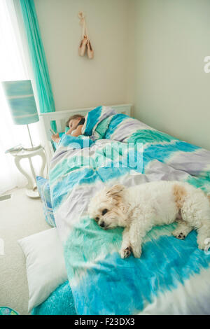 Les jeunes teenage Caucasian girl en utilisant son iphone au lit avant de se lever le matin avec son petit chien blanc couché Banque D'Images