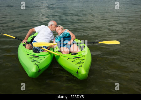 Senior couple in 70s portant des maillots de pause pour baiser tout en kayak dans un lac du Minnesota, Hackensack, USA Banque D'Images