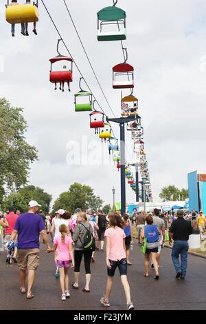 Des foules de gens marche sous un télésiège colorés ride à la Minnesota State Fair. Banque D'Images