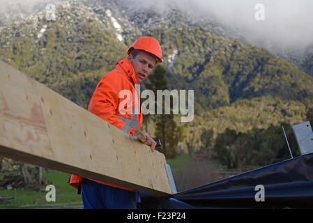 Un constructeur positionne une grande panne sur le toit d'un bâtiment Banque D'Images