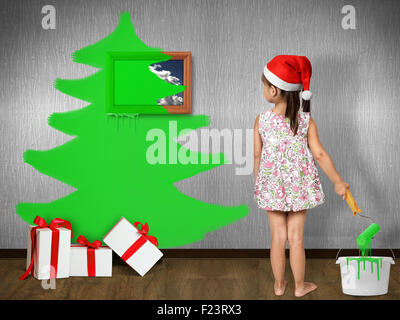 Enfant drôle habillé Santa hat, attire l'arbre de Noël sur le mur à la maison, concept de Noël Banque D'Images