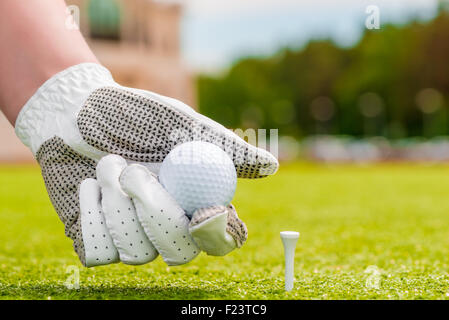 Libre de main tenant une balle de golf près de la pièce en T Banque D'Images