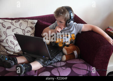 Petit garçon regardant la vidéo sur un ordinateur portable avec des écouteurs Banque D'Images