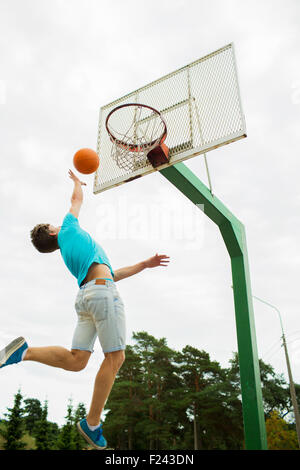 Jeune homme jouant au basket-ball extérieur Banque D'Images