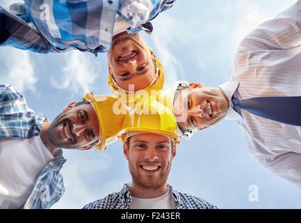 Close up of builders wearing hardhats in circle Banque D'Images