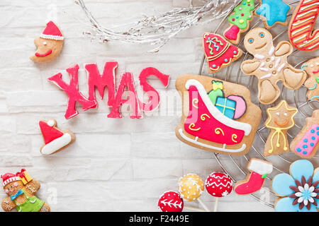 Noël cuisson. Différents types de cookies de décoration de Noël décoré avec du sucre glace sur grille de refroidissement et lettres de Noël Banque D'Images