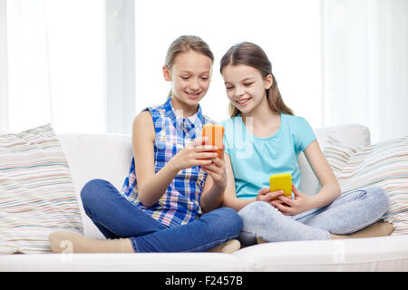 Heureux les filles avec les smartphones sitting on sofa Banque D'Images