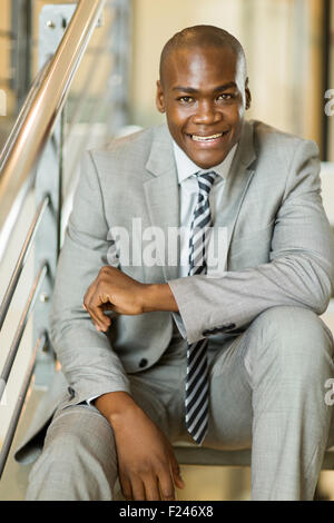 Happy young African American businessman sitting on stairs Banque D'Images