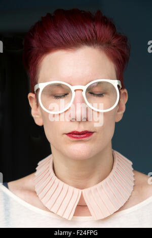 Portrait de la belle femme aux cheveux roux avec les yeux fermés et portant des lunettes blanc Banque D'Images