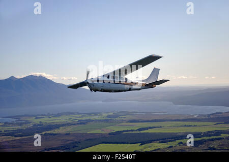 Un Cessna 210 sous pression vole au-dessus de la pittoresque côte ouest de la Nouvelle-Zélande Banque D'Images