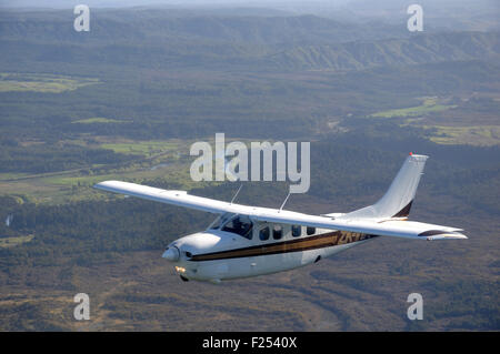 Un Cessna 210 sous pression vole au-dessus de la pittoresque côte ouest de la Nouvelle-Zélande Banque D'Images