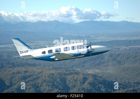 Un Piper Chieftain vole au-dessus de la pittoresque côte ouest de la Nouvelle-Zélande Banque D'Images