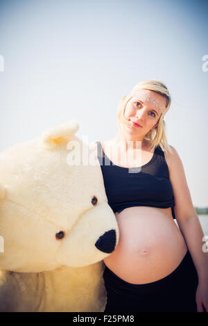 Portrait d'une jeune et belle femme enceinte avec un gros nounours. Banque D'Images