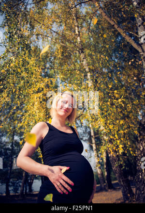 Portrait d'une jeune et belle femme enceinte parmi les arbres colorés Banque D'Images