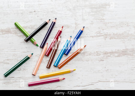 Vue de dessus d'un tas de crayons de couleur sur une table en bois blanc. Banque D'Images