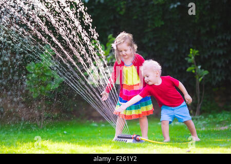 Enfant jouant avec jardin arroseur. Enfant d'âge préscolaire la course et le saut. Piscine d'été de plaisir de l'eau dans la cour. Banque D'Images