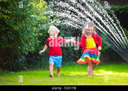 Enfant jouant avec jardin arroseur. Enfant d'âge préscolaire la course et le saut. Piscine d'été de plaisir de l'eau dans la cour. Banque D'Images