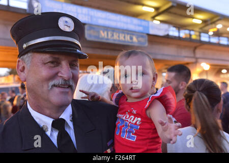 Merrick, New York, USA. Sep 11, 2015. RILEY E. GIES, one-year-old fille de Ronnie, chef des pompiers qui sont morts des gies e répondre aux attaques terroristes de New York le 11 septembre 2001, est détenu par CRAIG MALTZ, un pompier bénévole Bellmore, à Merrick Merrick Cérémonie commémorative pour les pompiers volontaires et les résidents qui sont morts en raison d'attentats terroristes à New York Tours Jumelles. Ex-Chief Ronnie E. Gies du Merrick F.D. et FDNY Squad 288 Ex-Captain, et Brian E. Sweeney, du Merrick F.D. et FDNY Rescue 1, est mort en réponse à des attaques du 11 septembre 2001. © Ann Parry/ZUMA/Alamy Fil Live News Banque D'Images