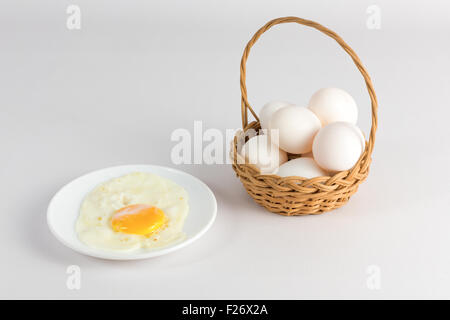 Œuf de poule frit dans une assiette blanche et un panier avec des oeufs Banque D'Images