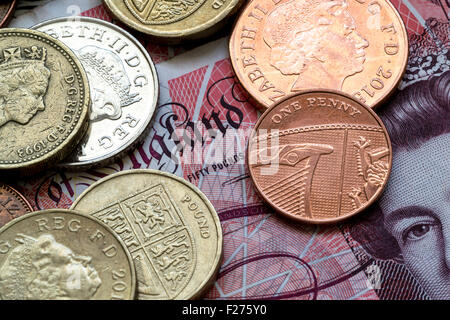 Un assortiment de pièces en anglais de différentes valeurs s'étendit sur un livre britannique cinquante note avec le Queens Head partiellement visible de onu Banque D'Images
